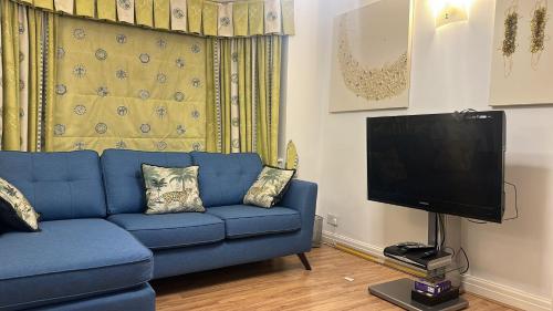 磨坊山2 Bed Mill Hill Flat的客厅配有蓝色的沙发和平面电视。
