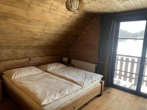 奇奇马尼Cabin House Čičmany- Relaxačné zariadenie s ubytovaním的木制客房的一张床位,设有窗户