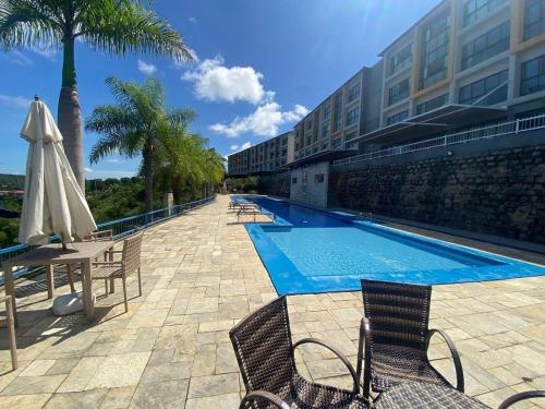 巴纳内拉斯Flat dos Sonhos Bananeiras的一座带椅子和遮阳伞的游泳池位于大楼旁