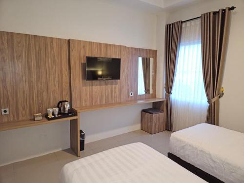 TjileungsirThe Safiina Point Syariah Hotel的酒店客房设有两张床和电视。