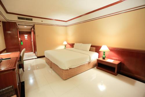 坤敬Kosa Hotel & Wellness Center -SHA Certified的一间卧室配有一张床和一张带台灯的桌子
