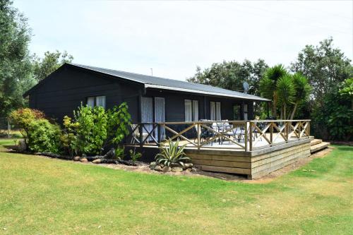 KaihuKai Iwi Lakes Resort的黑色房子,设有门廊和院子