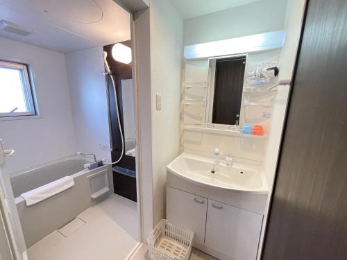 宜野湾市BiBi Hotel FUTENMA的白色的浴室设有水槽和浴缸。