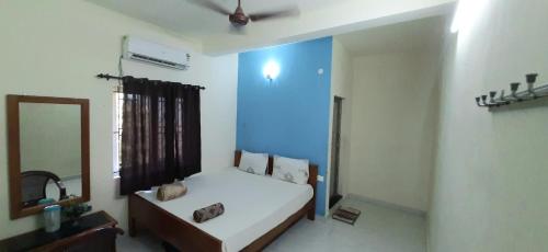 AlānduraiTeja Residency的一间卧室配有一张带镜子和蓝色墙壁的床