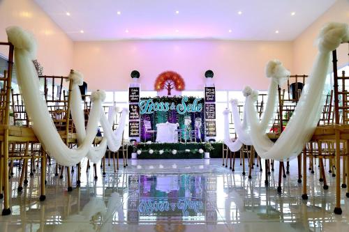 CalapanMahalta Resorts and Convention Center的一个带白色椅子和舞台的婚礼大厅