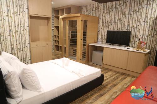 CalapanMahalta Resorts and Convention Center的卧室配有白色的床和电视。