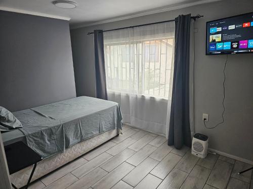 圣地亚哥Apartamento Interior 2do Piso Casa, 026 Quilicura的一间卧室配有一张床、一台电视和一个窗口