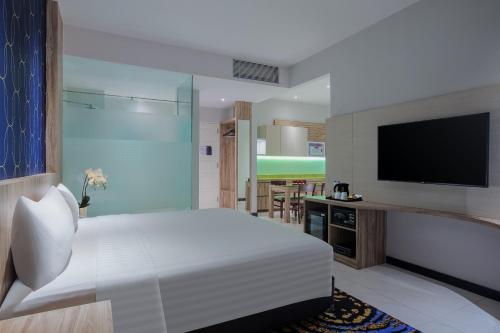 打横ASTON Inn Tasikmalaya的一间卧室配有一张床和一台平面电视