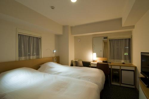 鹿儿岛鹿儿岛日光酒店的酒店客房设有白色的床和电视。