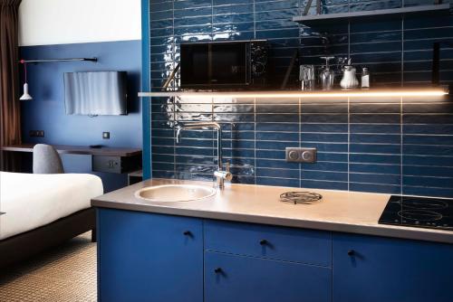 莫尔塞姆Hotel Le Bugatti的浴室配有水槽和蓝色瓷砖墙。
