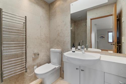 TitirangiBeachside Luxury - Laingholm Holiday Apartment的白色的浴室设有卫生间和水槽。