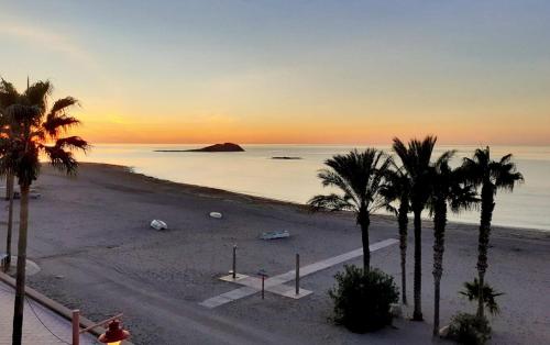 卡沃内拉斯Alboran hotel的日落时分拥有棕榈树和海洋的海滩