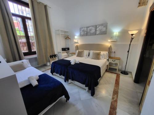 塞维利亚Casona de San Andrés的酒店客房设有两张床和窗户。