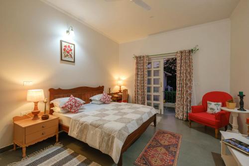 斋浦尔Shree Nikunj - A Boutique Homestay的一间卧室配有一张床和一张红色椅子