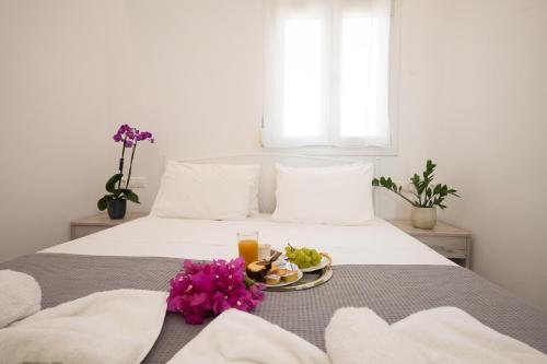 阿格拉瑞Spilia Apartments & Suites Mykonos的一张床上有一盘食物和鲜花的床