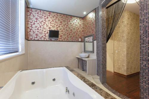 坡州市Carlton Hotel的带浴缸的浴室和墙上的电视