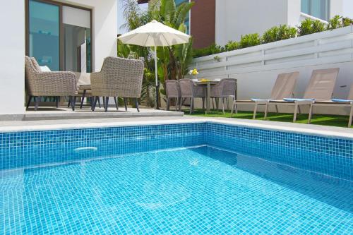 普罗塔拉斯Villa Dina的游泳池配有椅子和一张桌子及遮阳伞