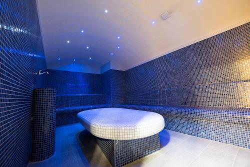 萨拉热窝岳罗普酒店的蓝色瓷砖浴室设有凳子和浴缸