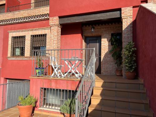 利纳雷斯Casa grande de tres plantas的红色的建筑,带有种有植物的阳台