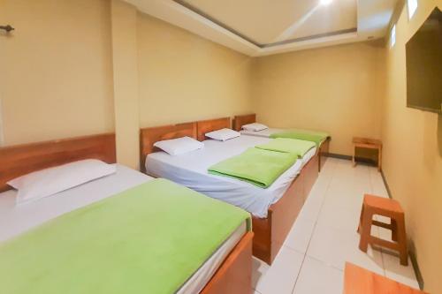 岩望Delvia Bromo Homestay Mitra RedDoorz的一间卧室配有两张带绿床单和椅子的床