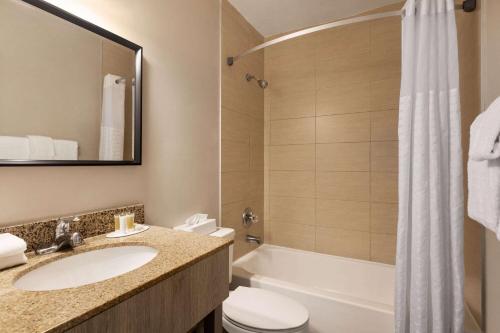 迈阿密迈阿密/机场北戴斯酒店的浴室配有盥洗盆、卫生间和浴缸。