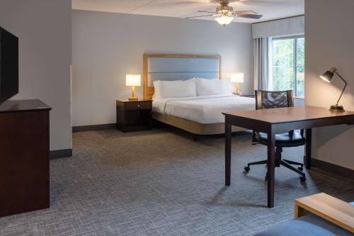罗切斯特纽约州罗彻斯特/希腊希尔顿惠庭套房酒店的配有一张床、一张桌子和一张桌子的酒店客房