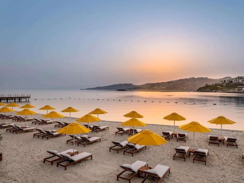 亚力卡瓦克MGallery The Bodrum Hotel Yalikavak的海滩上的一组椅子和遮阳伞