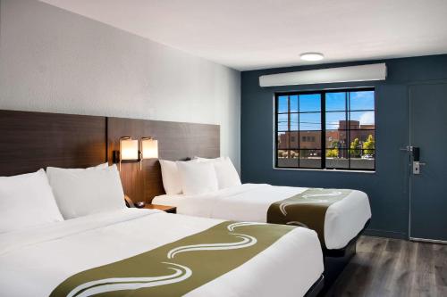 圣达菲Quality Inn Santa Fe New Mexico的酒店客房设有两张床和窗户。