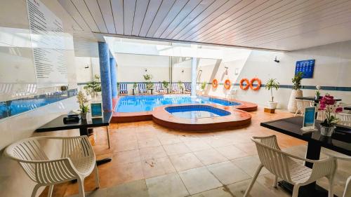 富查伊拉城市大厦酒店 的游泳池位于带桌椅的房间