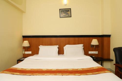 塞勒姆Hotel Shrie Shaanth的一间卧室配有一张大床和木制床头板