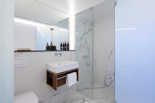 许克尔霍文TIN INN l Hückelhoven einfach gut - Das Hotel aus hochwertig ausgebauten Überseecontainern的白色的浴室设有水槽和淋浴。