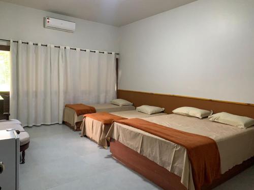 博尼托绿意盎然乡间宾馆的一间卧室设有两张床,窗户配有窗帘