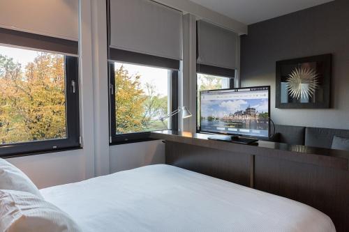 海牙肯尼迪B-公寓式酒店的一间卧室设有一张床、一台电视和窗户。