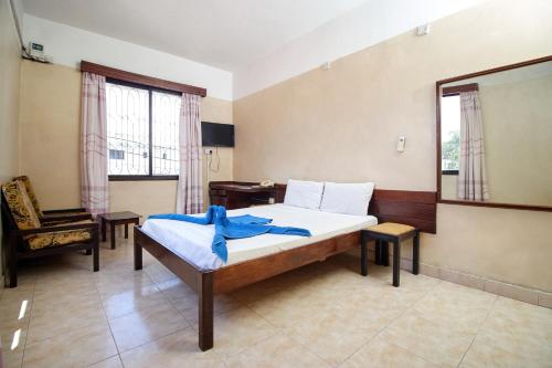 蒙巴萨Mombasa Railway Gardens Hotel的一间卧室配有一张床、一把椅子和窗户。