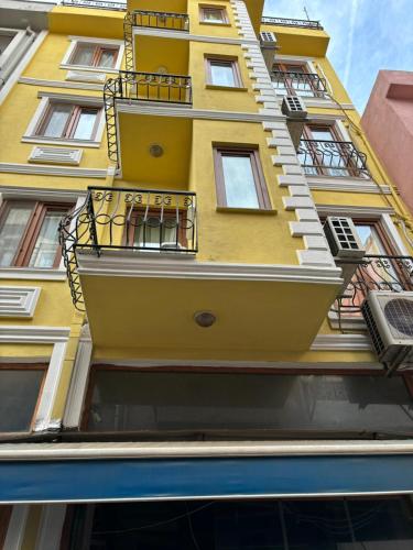恰纳卡莱Efe Can Apart Otel的黄色的建筑,旁边设有阳台