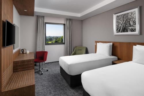 内罗毕Holiday Inn - Nairobi Two Rivers Mall, an IHG Hotel的一间酒店客房,设有两张床和电视