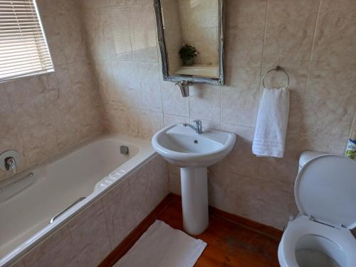 克拉伦斯Twogether House的一间带水槽、浴缸和卫生间的浴室