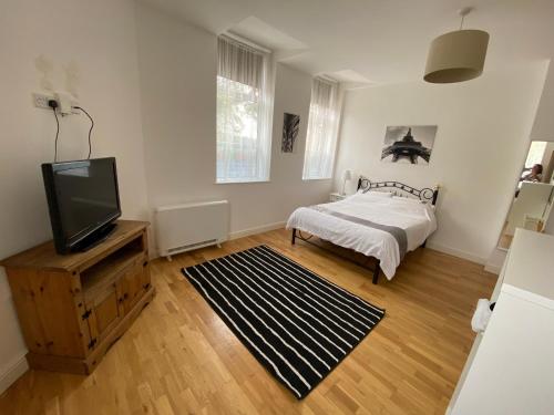 莱斯特Midland apartments- Open plan的一间卧室配有一张床和一台平面电视