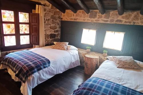 比努埃萨Casa Rural con encanto en plena Reserva de Urbión.的一间卧室设有两张床和两个窗户。