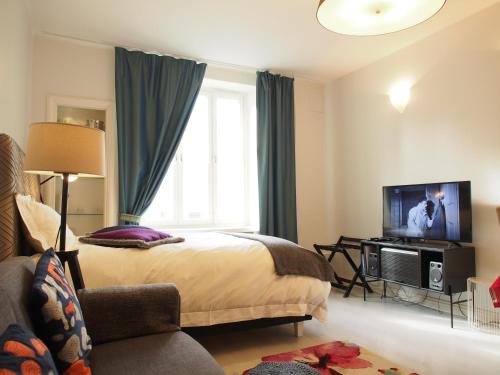 赫尔辛基Top Apartments Helsinki - Alppila的一间卧室设有一张床、一台电视和一个窗口。