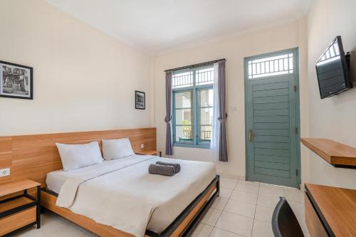 库塔旁东克安娅尔酒店的一间卧室配有一张带绿门的床和一台电视