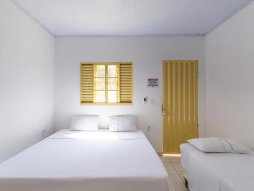 卡达斯诺瓦斯Pousada Caldas Novas的白色的客房设有两张床和窗户。
