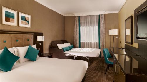 沃金沃金希尔顿逸林酒店的酒店客房,配有两张床和椅子