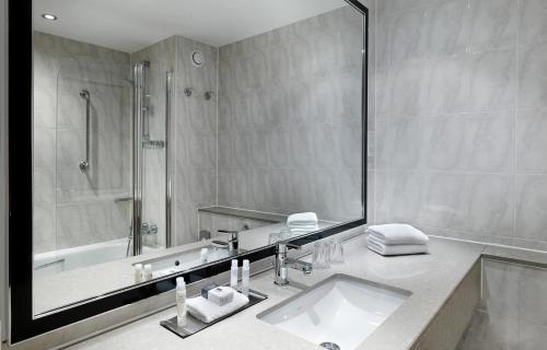 沃金沃金希尔顿逸林酒店的浴室配有水槽、淋浴和浴缸。