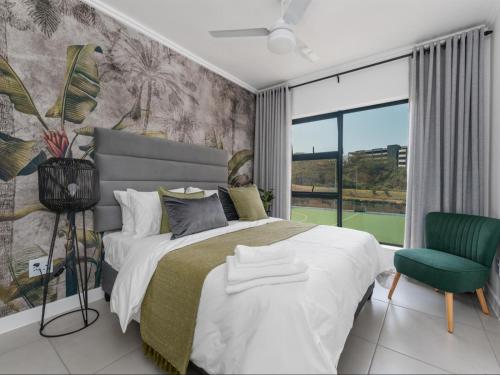 巴利托Ballito Village Luxury Apartments by DropInn的一间卧室配有一张大床和一张绿色椅子