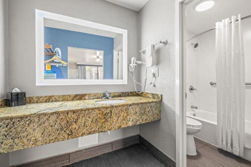 坦帕Quality Inn and Conference Center Tampa-Brandon的一间带水槽、卫生间和镜子的浴室