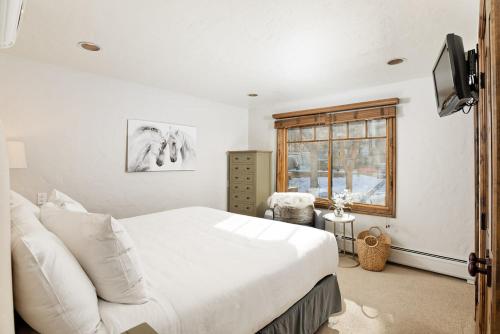 阿斯潘Fasching Haus Unit 310, Deluxe Condo w/ Stately Furnishings, Private Deck, A/C的卧室设有一张白色大床和一扇窗户。