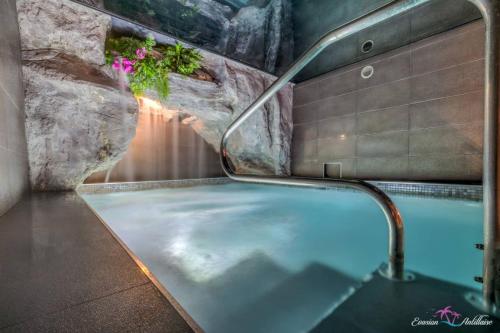马赛Evasion Antillaise的一间带岩石墙的浴室内的热水浴缸
