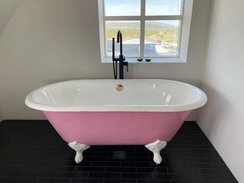 GodafossHótel Goðafoss Fosshóll的带窗户的浴室内的粉红色浴缸