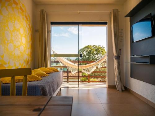 普腊亚罗萨Lugar ao Sol - Flats - Praia do Rosa - SC的一间卧室设有一张床和一个滑动玻璃门